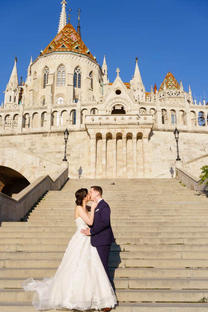 Elegáns, hajnali esküvői kreatív fotózás a Halászbástyánál Budapesten a Budai várban egy menyasszonnyal és egy vőlegénnyel.